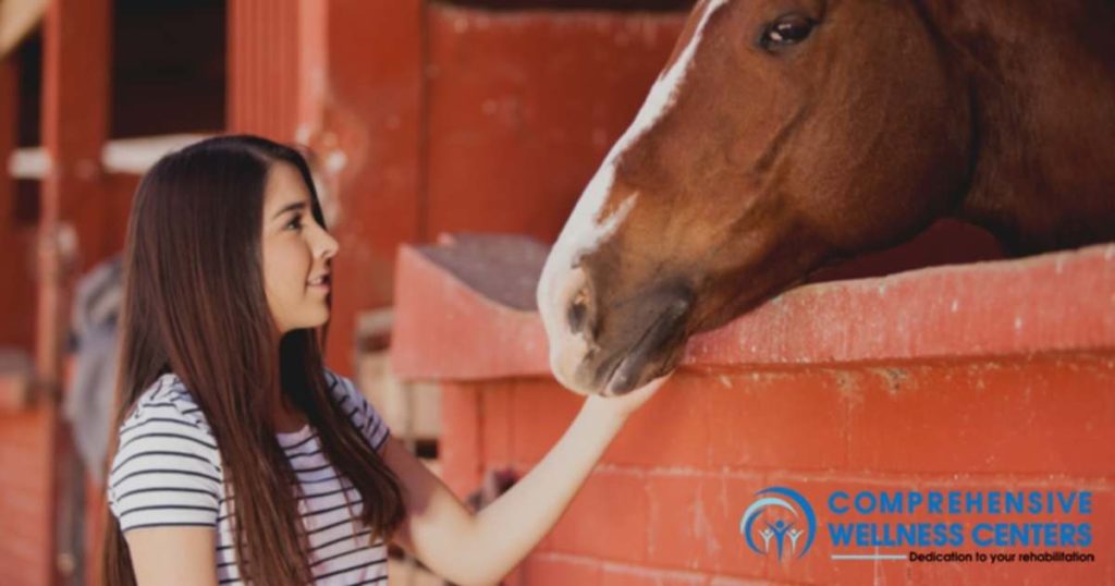 girl petting horse in animal-assisted therapy for addiction treatment